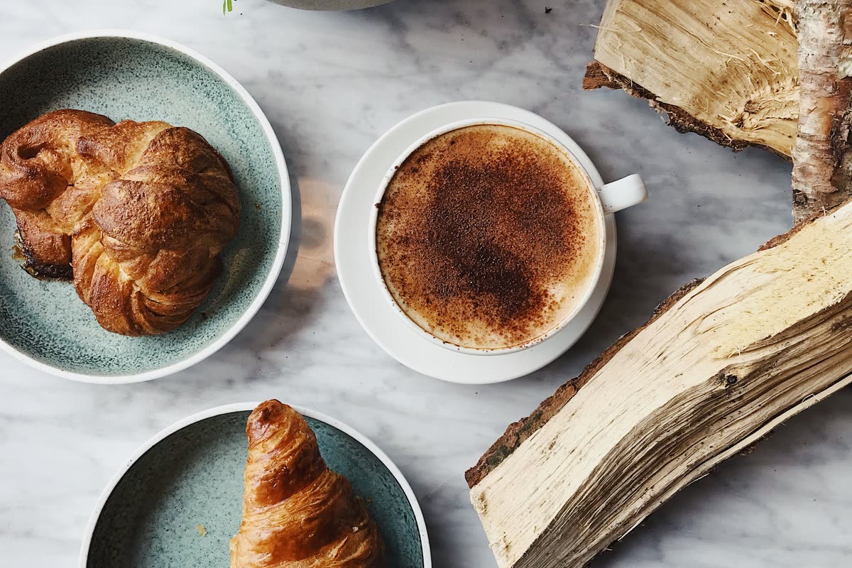 Croissanter, kanelbulle och kaffe på marmorbord